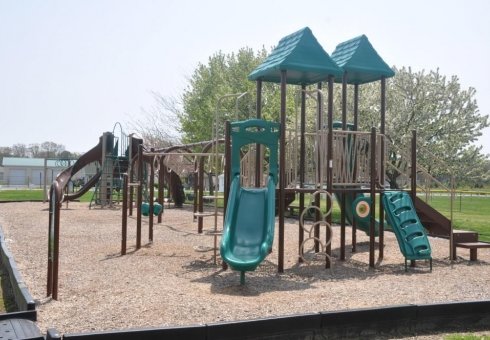 green and brown playground with double slides