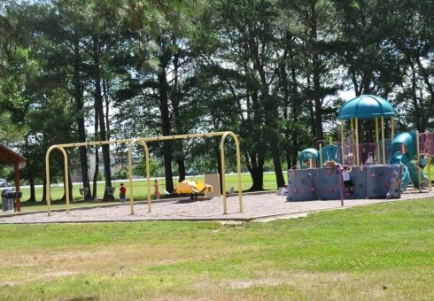 small dark colored playground with yellow swings 